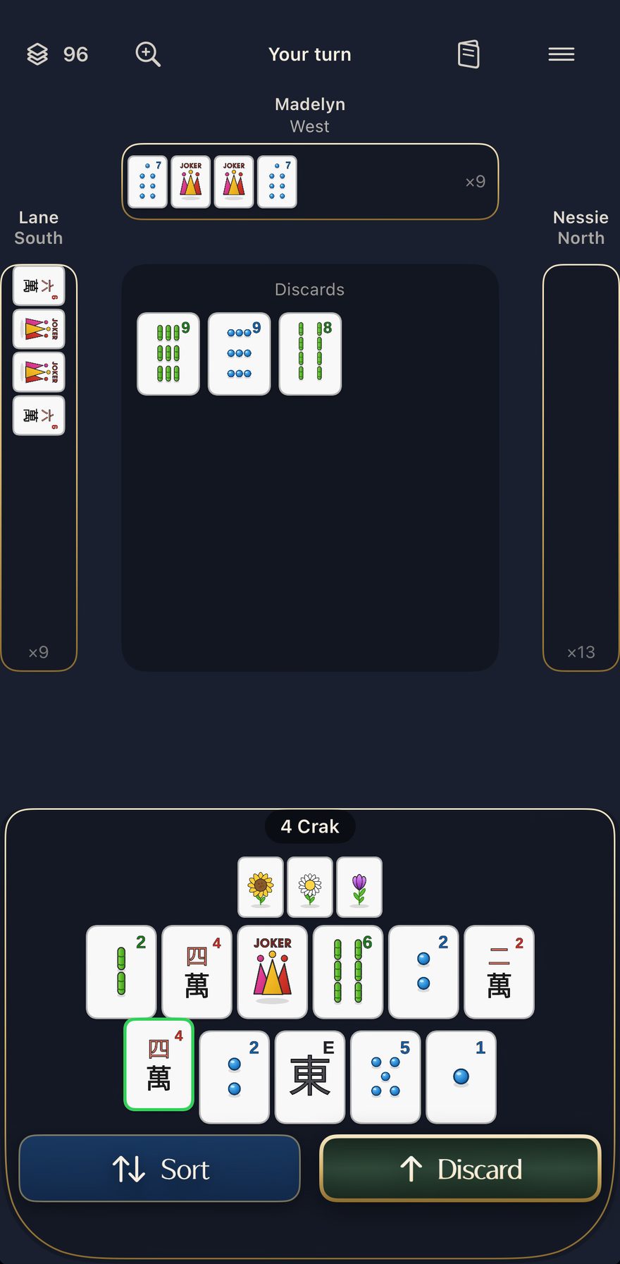 A mid-hand table on the app's Original theme, midnight navy. It is your turn: three tiles sit on the discard floor, West has exposed a pung of 7 dots using two jokers, and your own hand of flowers, bams, dots, craks and a joker is racked below with Sort and Discard buttons